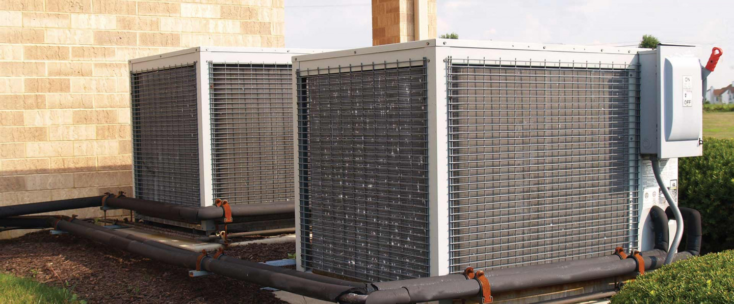 Two HVAC units side by side on the side of a building